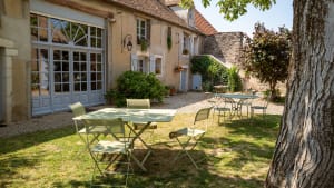 Cour intérieure avec tables vertes devant maison traditionnelle française.