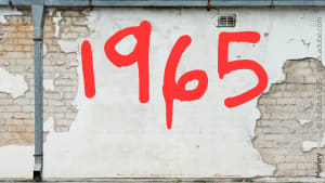 Numéro 1965 rouge sur mur blanc écaillé et fissuré. 1965
