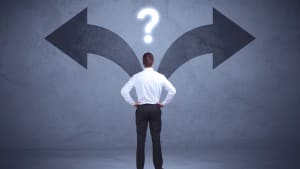 Homme d'affaires prenant une dcision tout en regardant les flches sur le mur comme concept