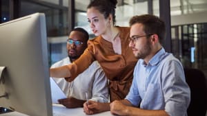 Une femmes montrent  deux hommes un lment sur un ordinateur.