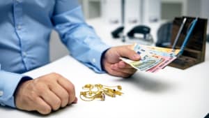 Un homme tendant une somme d'argent en change de bijoux en or