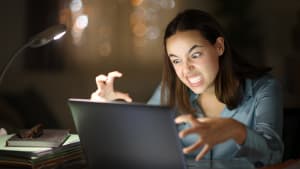 Employé en télétravail en colère utilisant un ordinateur portable la nuit