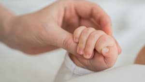 Un adulte tient la main d'un nourrisson.