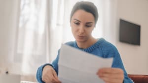 Femme d'affaires concentrée lisant des documents et travaillant depuis chez elle