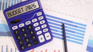 Budget 2026 inscrit sur une calculatrice, avec des documents budg�taires en fond.