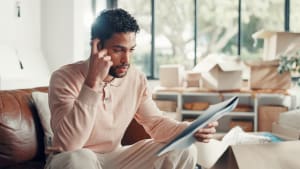 Homme examinant tablette dans salon avec cartons déménagement.