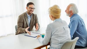 Homme discute avec couple �g� autour d'une table.