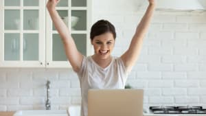 Une femme heureuse, devant son ordinateur.