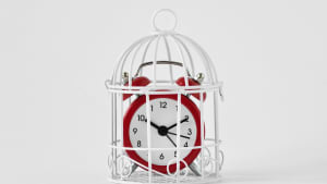 Un r�veil rouge dans une cage sur fond blanc.