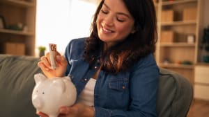 Une femme économisant de l'argent dans une tirelire.