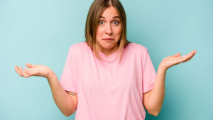 Jeune femme isol�e sur fond bleu, doutant et haussant les �paules dans un geste interrogateur.