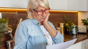 Une femme regarde un document l'air préoccupé.
