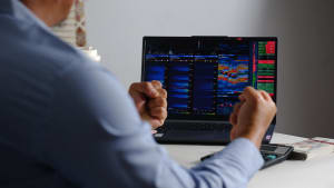 Vue par-dessus l'épaule d'un trader analysant un graphiques avec une expression heureuse.