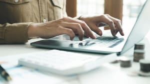 Femme comptable travaillant sur un ordinateur portable tout en calculant les impôts en ligne.