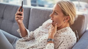 Maison, femme choqu�e sur le canap�, smartphone et application num�rique pour les m�dias sociaux. Surprise, wow et personne sur le canap�, t�l�phone portable ou email avec connexion, notification de texte ou message pour contacter et omg