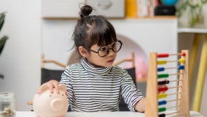 Petite fille avec lunettes joue avec un abaque color�.