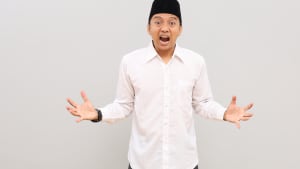 Un homme musulman asiatique avec un geste de col�re, criant avec les paumes ouvertes, debout isol� sur fond gris.