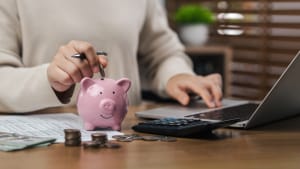 Une femme calcule ses imp�ts, y compris en d�posant des pi�ces dans une tirelire, �conomisant de l'argent, planifiant, investissant, budg�tisant, �conomisant de l'argent et assurant la croissance financi�re pour l'avenir.