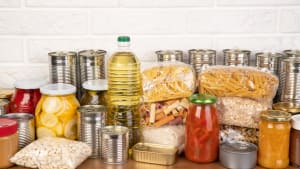 Des dons de nourriture tels que des p�tes, du riz, de l'huile, du beurre de cacahu�te, des conserves, de la confiture et autres sur une table brune.