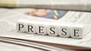 Dés cubiques formant le mot PRESSE sur des journaux.