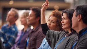 Femme d'affaires en pr�sentation lors d'une conf�rence levant la main pour poser une question