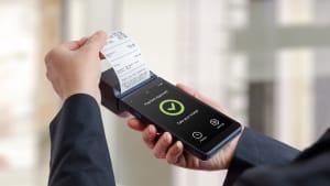 Client tenant un terminal de paiement portable avec un reçu imprimé et un écran de paiement approuvé, représentant un encaissement réussi, l'achèvement d'une transaction de vente au détail et des systèmes de paiement électroniques modernes