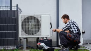 Technicien effectuant l'entretien d'une unité de pompe à chaleur extérieure.