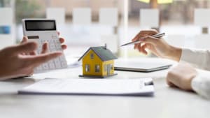 Deux personnes discutent d?un pr�t immobilier avec une calculatrice.