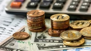 Des pi�ces de bitcoin, des dollars et une calculatrice sur table.