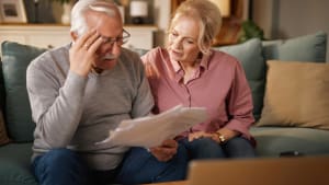 Un homme et une femme �g�es regardent des documents assis sur un canap�.
