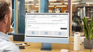 Homme travaillant sur un ordinateur, �cran affichant biens immobiliers.