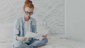 Une belle femme rousse freelance regarde attentivement les documents, calcule et gère les finances