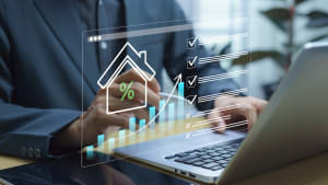 Homme travaillant sur ordinateur avec graphiques immobiliers virtuels.