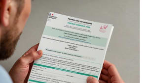 Un homme tient un formulaire de demande de chèque énergie.