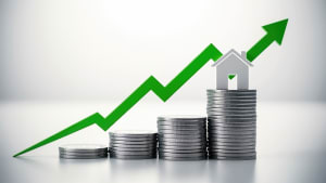 Des pièces de monnaie, une maison, flèche verte montante, croissance.