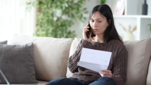 Une femme tenant un document, au téléphone.
