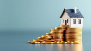 Maison posée sur des piles de pièces de monnaie dorées.