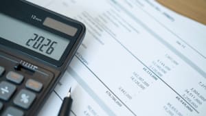 Calculatrice affichant 2026, documents financiers et stylo pr�sents.