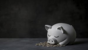 Tirelire cochon blanche avec pièces de monnaie devant elle.