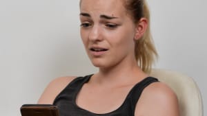 jeune femme �motionnelle au t�l�phone portable smartphone mimique effray�e