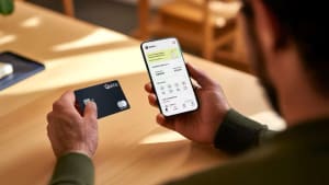 Homme tenant une carte bancaire et un smartphone Qonto.