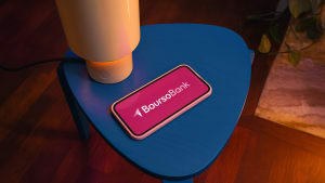 T�l�phone affichant BoursoBank sur une table bleue, lampe allum�e.