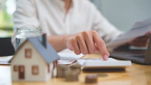 Personne calcule des finances immobili�res avec maison miniature et pi�ces.