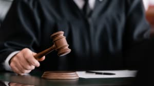 vue partielle du juge flou en robe tenant un marteau dans un tribunal