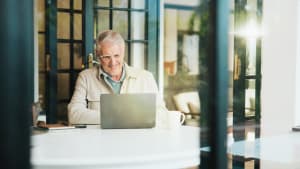 Heureux, � la maison et homme �g� sur ordinateur portable pour la banque en ligne, le paiement num�rique et le compte financier. Retraite, maison et personne mature sur ordinateur pour la finance, l'assurance ou l'investissement d'�pargne sur le site web