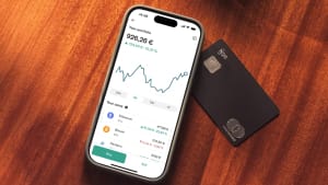 T�l�phone affichant portefeuille crypto et carte bancaire sur une table.