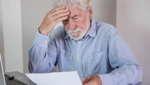 Un vieil homme paraissant stress� en lisant des documents � son bureau.