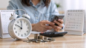 R�veil, pi�ces, calendrier, femme utilisant smartphone et calculatrice sur table.