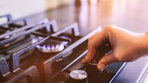 Une main tournant le brûleur à gaz d'une cuisinière