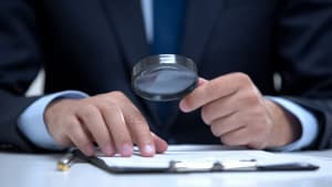 Avocat lisant un document avec une loupe, étudiant le cas en détail, enquête